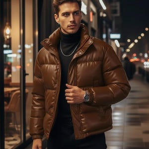 May include: A brown puffer jacket with a high collar. The jacket has a quilted design and a front zipper closure. The person is wearing a black turtleneck and a silver chain necklace. The background is a city street at night.