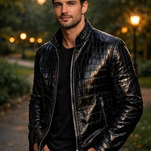 May include: A black leather jacket with a textured, crocodile-like pattern. The jacket has a zip-up front and a stand-up collar. The person is wearing a black t-shirt and black pants.