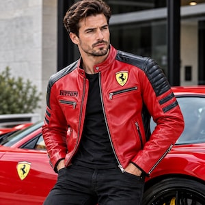May include: A red and black leather motorcycle jacket featuring a stand-up collar, silver-tone zippers, and the Ferrari logo on the chest. The jacket includes black quilted shoulder panels and the word Ferrari printed in black on the right chest.