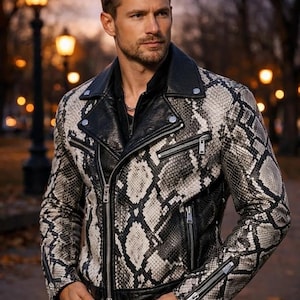 May include: A snakeskin-patterned leather jacket in black and white, featuring a black collar and zippers. The jacket has a classic biker style with a notched lapel and multiple pockets. The jacket is worn over a black shirt.