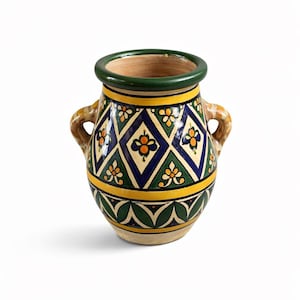 May include: A ceramic vase with a green rim and handles. The vase features a geometric pattern of blue diamonds, yellow stripes, and green leaves. The handles are a light brown color.