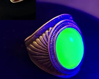 May include: A silver ring with a large, round, green gemstone. The stone glows brightly under a black light.