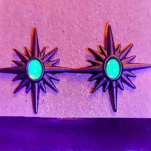 Peut inclure: Une paire de boucles d'oreilles en forme d'étoile noire avec des accents de gemmes vertes. Les boucles d'oreilles ont un design d'étoile pointue avec un centre surélevé.