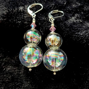 May include: A pair of iridescent glass bead earrings with silver hooks and pink crystal accents.
