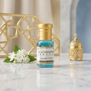 以下が含まれることがあります： 金色のキャップと「AL-USMANIAH PERFUME Leader (UAE)」と書かれたラベルが付いた、小さなターコイズブルーの香水瓶。 大理石の表面に置かれ、白い花と金色の装飾品が隣にあります。 小さな、装飾的な金色の容器も表示されています。