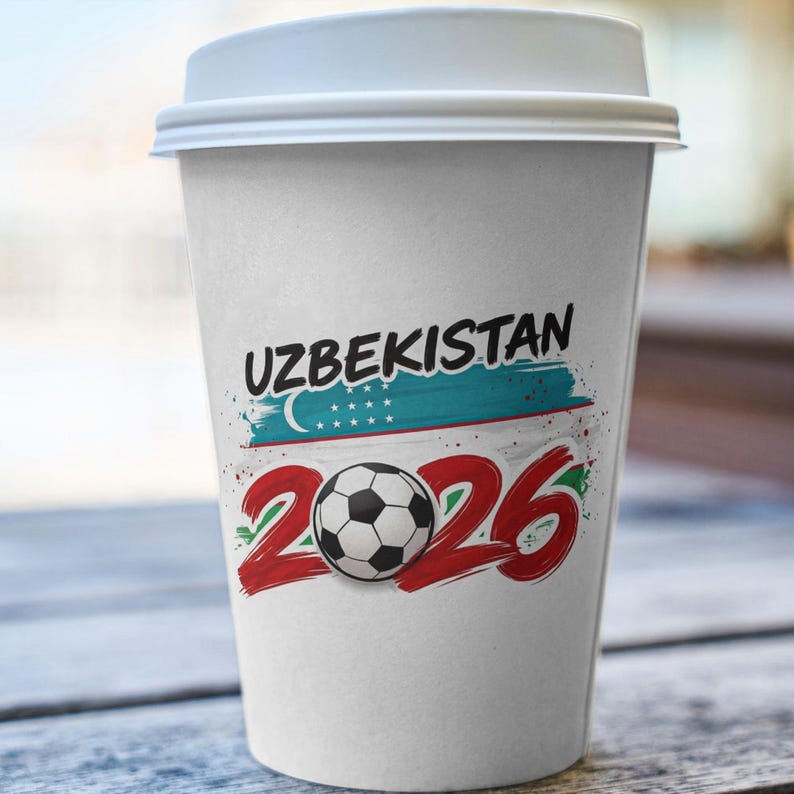 May include: A white paper coffee cup with a white lid. The cup features the word "UZBEKISTAN" in black, a blue and green flag design, and the number "2026" in red with a soccer ball in the center.