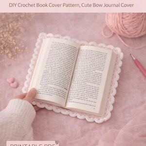 May include: A crochet book cover pattern PDF with the text "Crochet Notebook Cover Pattern PDF". The open book is surrounded by a white and pink crocheted border. A ball of pink yarn and a crochet hook are also visible.