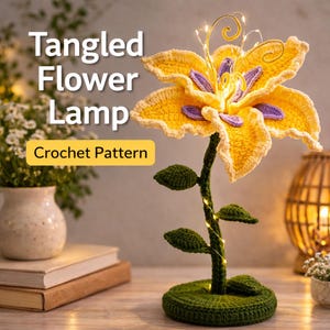 Puede incluir: Lámpara de flores de ganchillo con un diseño de flor amarilla y morada. La lámpara tiene un tallo y una base verdes, con pequeñas hojas y luces de hadas. El texto "Tangled Flower Lamp" y "Crochet Pattern" son visibles.