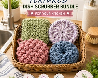 May include: A bundle of four different textured dish scrubbers in a woven basket. The set includes a square sage green scrubber, a round lavender and white swirled scrubber, a round dusty pink textured scrubber, and a round blue donut-shaped scrubber.