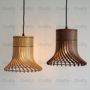 Puede incluir: Dos lámparas colgantes de madera, una clara y otra marrón oscuro. Tienen una parte superior cilíndrica y una base acampanada y curvada. Suspendidas por cables negros, cuelgan sobre un fondo blanco. La palabra "Crafty" se repite.