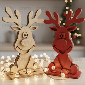 May include: Two wooden reindeer figurines, one in a natural light wood finish and the other in a solid red finish. Each reindeer features a cartoon-style face with large eyes, a round nose, a wide smile, and branched antlers, mounted on a flat base.