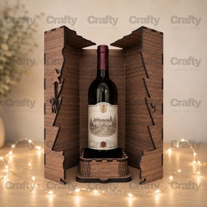 Pode incluir: Uma caixa de madeira castanho-escura para garrafas de vinho com bordas cortadas a laser em forma de árvore estilizada. A caixa está aberta, revelando uma garrafa de vinho de vidro escuro com um rótulo creme com um edifício e um brasão dourado.