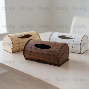 May include: Three wooden tissue box holders in light brown, dark brown, and white. Each has an oval opening and a curved, barrel-like shape. The boxes are made of laser-cut wood. Measurements are in centimeters.