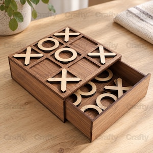 May include: A wooden tic-tac-toe game set featuring a square board with a grid pattern and a pull-out storage drawer. The board surface displays light-colored wooden X and O game pieces arranged in play, with additional pieces stored inside.