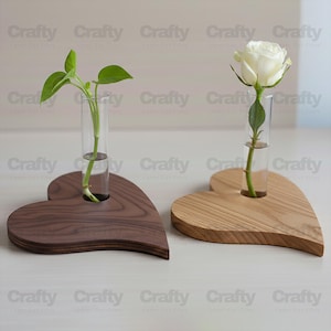 May include: Two heart-shaped wooden vases, one dark brown and one light brown, each holding a glass tube. One tube contains a green plant, the other a white rose. The word "Crafty" is repeated across the top and bottom of the image.