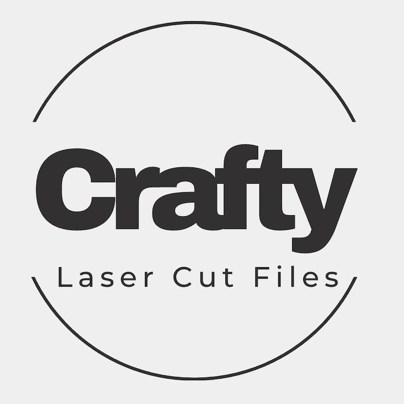 May include: A black and white logo with the word "Crafty" in bold letters, encircled by a partial black circle. Below the word "Crafty" is the text "Laser Cut Files". The background is a light gray.