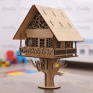 Puede incluir: Maqueta de casa en el árbol de madera con intrincados detalles recortados. La casa tiene un tejado inclinado, ventanas y un balcón decorativo. Está sostenida por una base de tronco de árbol. La palabra "Crafty" se repite varias veces.