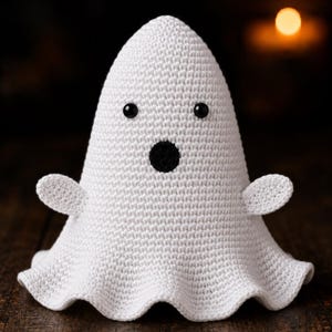 May include: A white crocheted ghost figurine with a rounded top, a flared base, and two small side arms. The ghost features two small black circular eyes and a larger black circular mouth, all crafted with a tight, uniform stitch pattern.