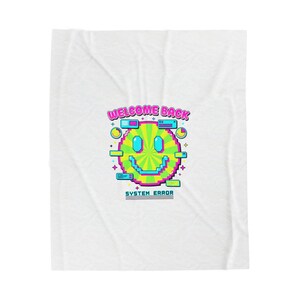 Peut inclure: Couverture blanche avec un motif de visage souriant pixélisé. Le visage souriant est vert et jaune avec des yeux bleus et une bouche souriante. Le texte "WELCOME BACK" et "SYSTEM ERROR" sont au-dessus et en dessous.