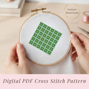 Puede incluir: Un patrón de punto de cruz en un bastidor de bordado de madera. El patrón presenta un diseño geométrico verde y amarillo sobre tela blanca. Las palabras "Descarga instantánea" están en un círculo dorado. El texto "Patrón de punto de cruz PDF digital" está en la parte inferior.