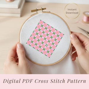 Puede incluir: Un patrón de punto de cruz en un bastidor de madera. El diseño presenta un patrón en forma de diamante de flores rosas con detalles verdes y amarillos. El texto "Instant Download" está en un círculo dorado.