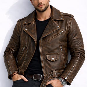 May include: Brown leather biker jacket with a distressed finish. It features a notched collar, multiple zipped pockets, and a waist belt. The jacket has a classic design, with a vintage appearance.
