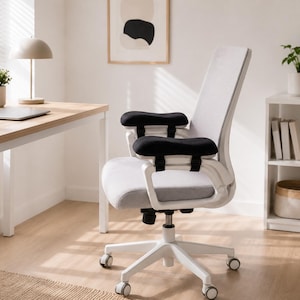 May include: A modern office chair with a white frame, gray seat and back, and black armrests. The chair has a five-wheel base and is positioned in a well-lit office space with a desk and decorative items.