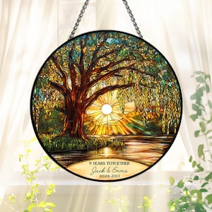 May include: A round stained glass window featuring a tree with a setting sun over a body of water. The artwork includes the text "9 YEARS TOTGETHER" and the names "Jack & Emma" with the years "2008-2017". The window is suspended by a chain.