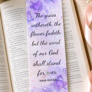 May include: A rectangular bookmark with a watercolour design in shades of purple and gold, featuring the quote "The grass withereth, the flower fadeth: but the word of our God shall stand for ever." Isaiah 40:8 KJV.