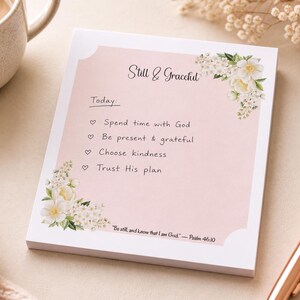 May include: A pink notepad with the words "Still & Graceful" and a list of affirmations. Floral accents adorn the corners. The text includes "Spend time with God," "Be present & grateful," "Choose kindness," and "Trust His plan."
