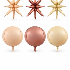 Pode incluir: Uma variedade de balões metálicos em dourado, cobre e bege. A imagem apresenta balões em forma de estrela e esféricos, ideais para decorações de festas. Os balões estrela têm várias pontas, enquanto as esferas têm um detalhe de costura e uma pequena cauda.