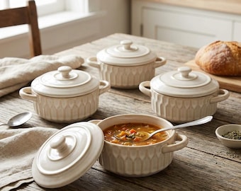 May include: A set of four cream-colored ceramic soup bowls with matching lids, each featuring two side handles and a vertical ribbed pattern. One bowl is open, filled with vegetable soup and a silver spoon, while the others are closed.