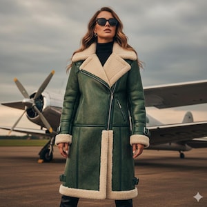 May include: A woman wearing a dark green shearling coat with cream-colored lining and trim, black sunglasses, and a black turtleneck. The coat has a zipper closure and buckle details. A vintage airplane is in the background.