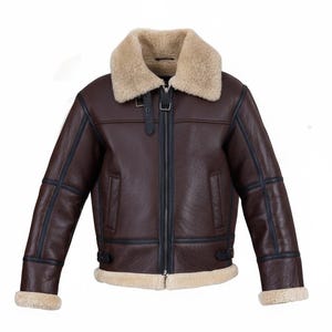 Puede incluir: Chaqueta de cuero marrón con cuello y forro de borrego beige. La chaqueta presenta una cremallera, ribetes negros y detalles de hebilla. Un estilo aviador clásico.