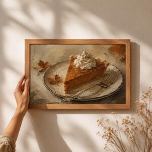 Può includere: Un dipinto a olio incorniciato raffigurante una fetta di torta di zucca guarnita con un ciuffo di panna montata su un piatto bianco, accompagnata da una forchetta d'argento e due piccole foglie autunnali secche, in stile materico.
