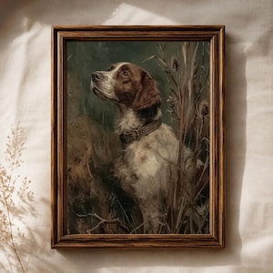 May include: A framed oil painting depicting a brown and white hunting dog with a leather collar, positioned among tall grasses and thistles. The artwork is enclosed in a dark brown wooden frame with a textured finish and visible wood grain.