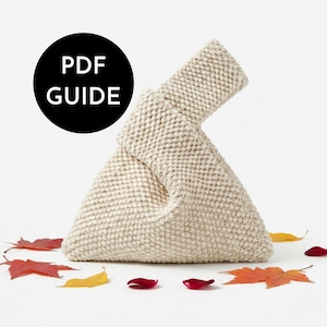 May include: A cream-coloured, triangular-shaped knitted bag with a single handle, featuring a textured stitch pattern. A black circular graphic in the upper left corner contains the white text PDF GUIDE. Scattered autumn leaves surround the bag.