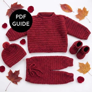 May include: A handmade, red crochet baby outfit set, including a jumper, trousers, hat with a pom-pom, and booties. The set is displayed with autumn leaves and rose petals. The image includes the text "PDF GUIDE" in a black circle.