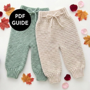 May include: Two pairs of handmade crochet baby pants in soft green and beige. Each pair has a drawstring waist and ribbed cuffs. The image includes fall leaves and the text "PDF GUIDE" in a black circle.