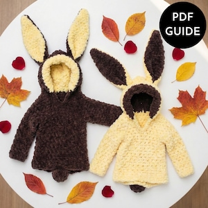 May include: Two handmade crochet bunny hoodies, one brown and one yellow, with long ears and a hood. The hoodies are displayed on a white surface with autumn leaves and rose petals. A black circle with the text "PDF GUIDE" is in the upper right corner.