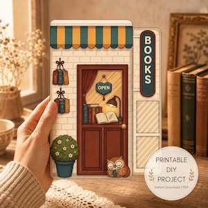 May include: A printable DIY project featuring a flat illustration of a bookstore facade with a striped awning, a door with an open sign, a lamp, books, a potted plant, and an owl reading a book. The text BOOKS is displayed on a vertical sign.