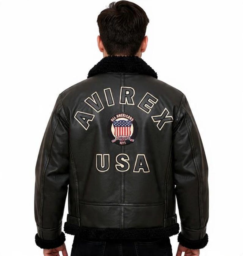 May include: Black leather jacket with a shearling collar and cuffs. The back displays the text "AVIREX USA" and an emblem of the American flag. The jacket has a classic aviator style.