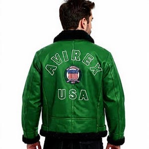May include: Green leather jacket with black faux fur collar and trim. The back displays the white text "AVIREX USA" and a circular emblem. A classic bomber jacket style.