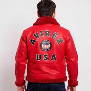 May include: Red leather jacket with a shearling collar and trim. The back of the jacket features the word "AVIREX" arched above a circular emblem and the word "USA" below. The jacket is a classic bomber style.