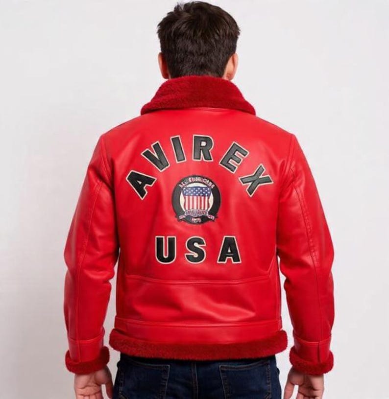 May include: Red leather jacket with a shearling collar and trim. The back of the jacket features the word "AVIREX" arched above a circular emblem and the word "USA" below. The jacket is a classic bomber style.