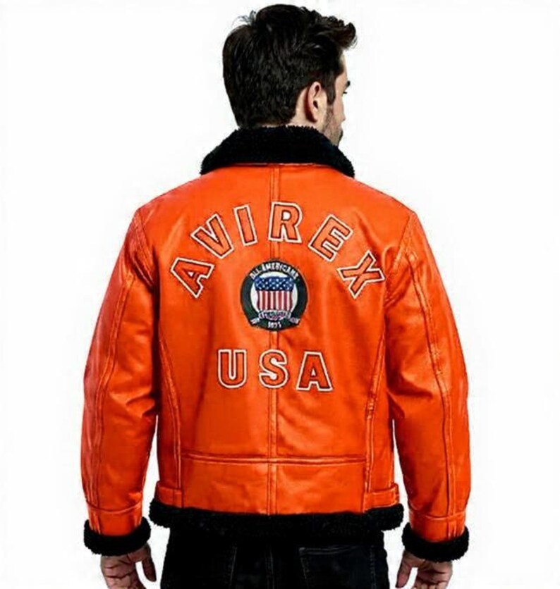 May include: Orange leather jacket with black faux fur collar and cuffs. The back of the jacket features the text "AVIREX USA" with an emblem. A classic bomber jacket style.