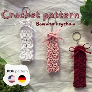Può includere: Tre portachiavi all'uncinetto fatti a mano in bianco, rosa e bordeaux, ciascuno con un fiocco di nastro e un portachiavi in metallo. Il testo "Crochet pattern Bownita keychain" è visualizzato sopra. È disponibile un modello PDF.
