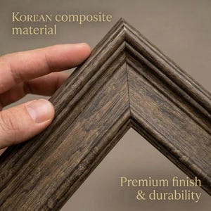 May include: Close-up of a corner of a brown wooden picture frame. The frame has a textured, grooved design and is made of Korean composite material. The text "Premium finish & durability" is visible.