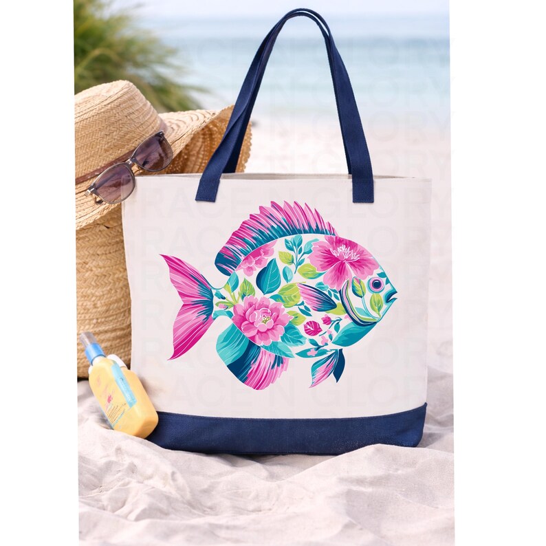 May include: White canvas tote bag with a navy blue base and handles. The bag features a colorful fish design filled with pink and teal flowers and leaves. A straw hat, sunglasses, and sunscreen are in the background.