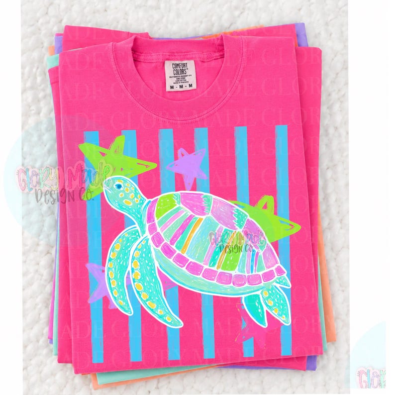 May include: A bright pink short-sleeve t-shirt featuring a graphic of a sea turtle with a multi-colored striped shell. The design includes vertical light blue stripes and several lime green and purple stars. The neck label reads Comfort Colors M.
